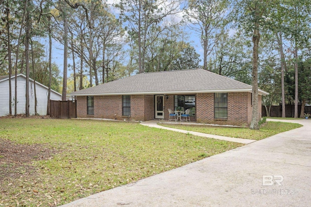 single story home featuring brick siding, roof with shingles, a front yard, and fence