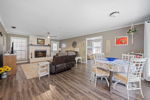 dining room with plenty of natural light, dark wood-type flooring, a brick fireplace, and visible vents