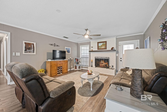 living room featuring light wood-style floors, a healthy amount of sunlight, and ornamental molding