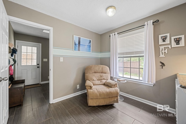 living area with wood finish floors, a textured ceiling, and baseboards