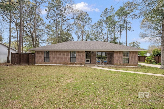 ranch-style house featuring a shingled roof, a front yard, brick siding, and fence