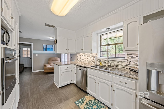 kitchen with stainless steel appliances, decorative backsplash, white cabinets, a sink, and a peninsula