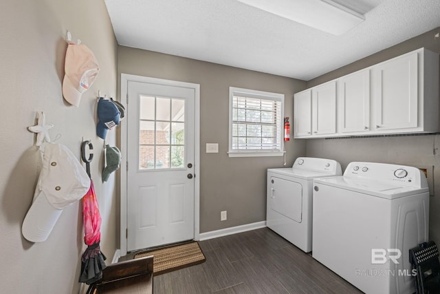 laundry area featuring a textured ceiling, baseboards, independent washer and dryer, cabinet space, and wood tiled floor