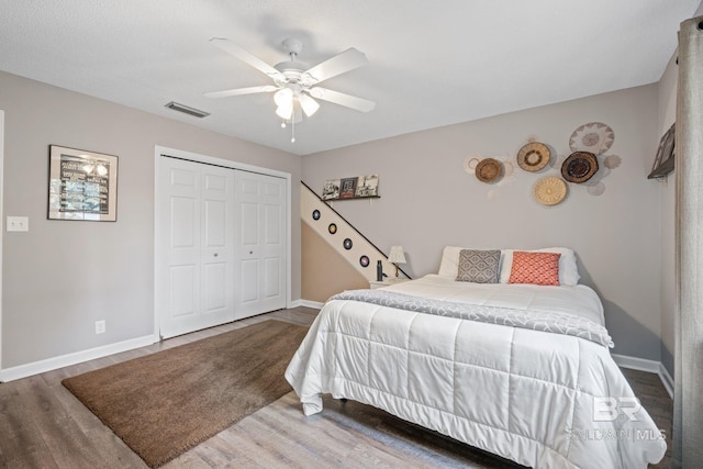 bedroom with a closet, visible vents, baseboards, and wood finished floors