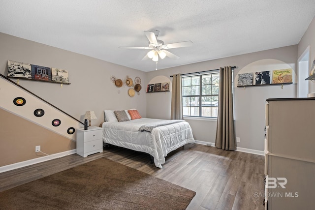 bedroom featuring a textured ceiling, ceiling fan, wood finished floors, and baseboards