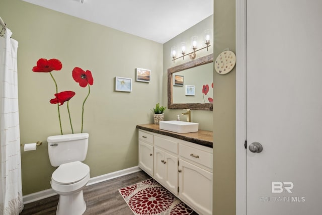 bathroom featuring toilet, vanity, baseboards, and wood finished floors