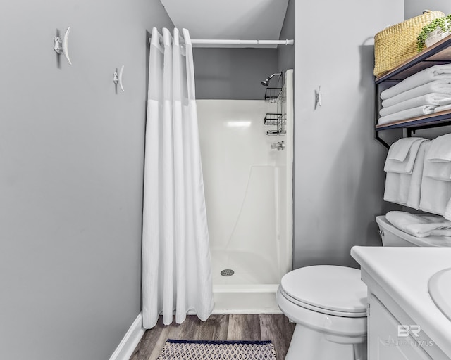 full bathroom featuring toilet, wood finished floors, vanity, baseboards, and a stall shower