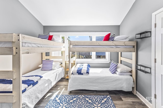 bedroom with lofted ceiling, baseboards, and dark wood-style flooring