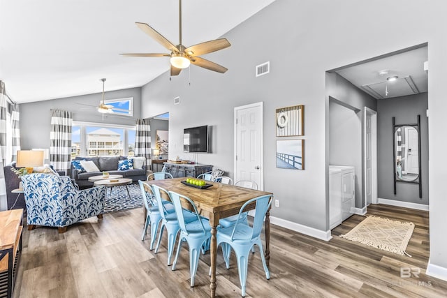 dining area featuring washing machine and clothes dryer, visible vents, attic access, ceiling fan, and wood finished floors