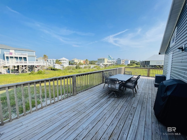 wooden terrace featuring outdoor dining space, area for grilling, and a residential view