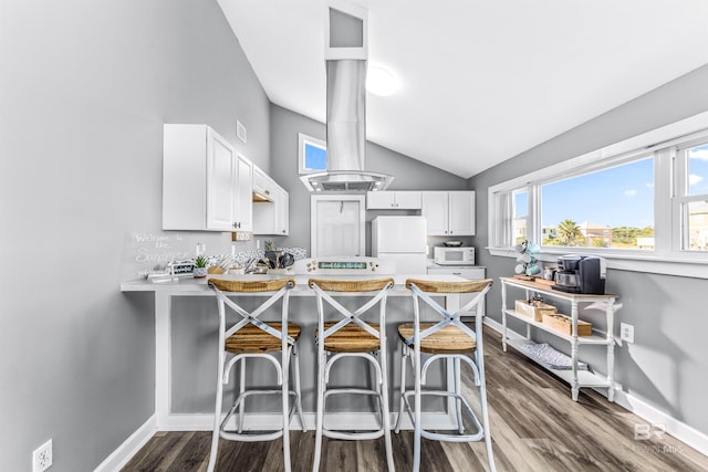 kitchen featuring a breakfast bar, light countertops, white appliances, and white cabinets