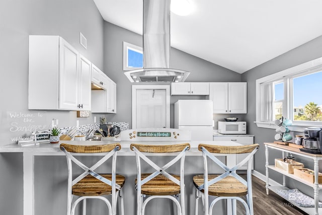 kitchen with light countertops, white appliances, a kitchen bar, and island range hood