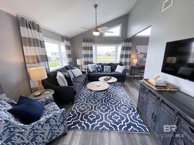 living area with a healthy amount of sunlight, dark wood-style floors, visible vents, and a ceiling fan