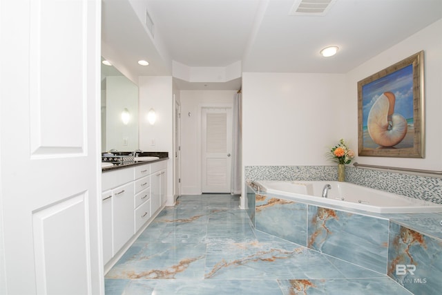 bathroom featuring vanity and a relaxing tiled tub