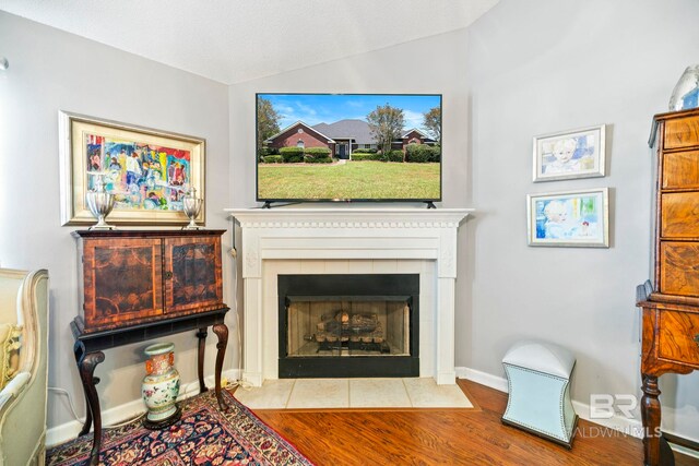 living room featuring a fireplace, light hardwood / wood-style flooring, a textured ceiling, and lofted ceiling