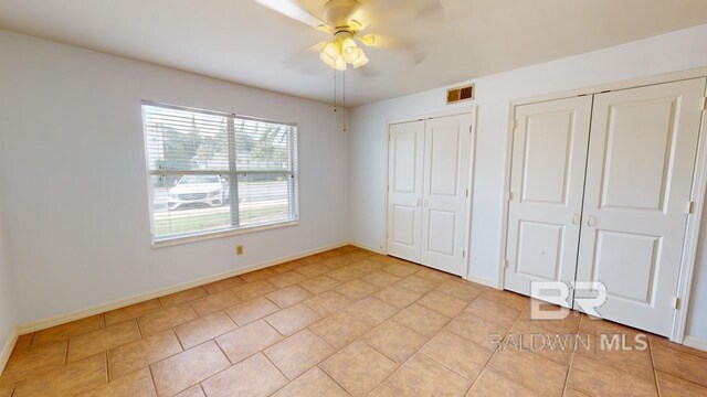 unfurnished bedroom featuring ceiling fan and two closets