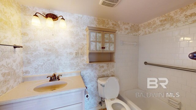 full bathroom featuring tiled shower / bath combo, vanity, and toilet