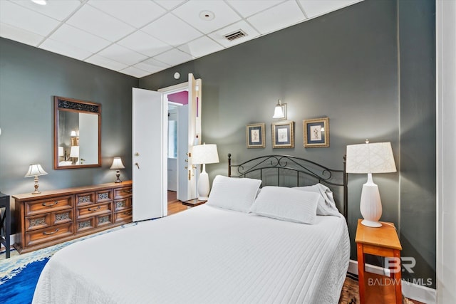 bedroom with wood-type flooring and a paneled ceiling