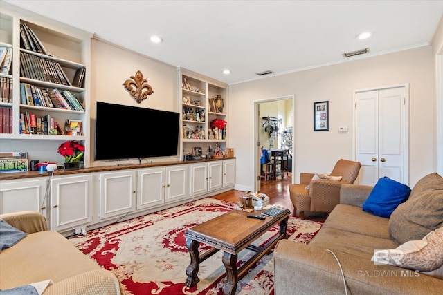 living room featuring light wood-type flooring, ornamental molding, and built in features