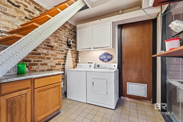 laundry room featuring brick wall, separate washer and dryer, cabinets, and light tile patterned flooring