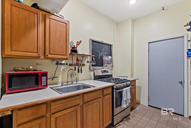 kitchen featuring light tile patterned floors, stainless steel gas stove, and sink