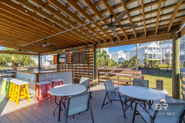 deck featuring outdoor dining space, a lawn, outdoor dry bar, and ceiling fan