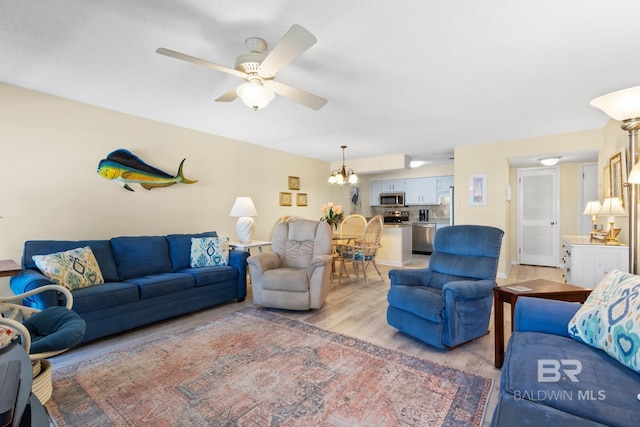 living room with light wood-style flooring and ceiling fan with notable chandelier