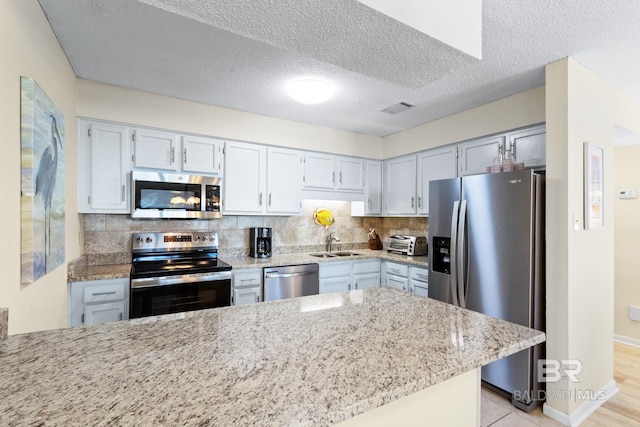 kitchen with stainless steel appliances, light stone countertops, tasteful backsplash, and visible vents