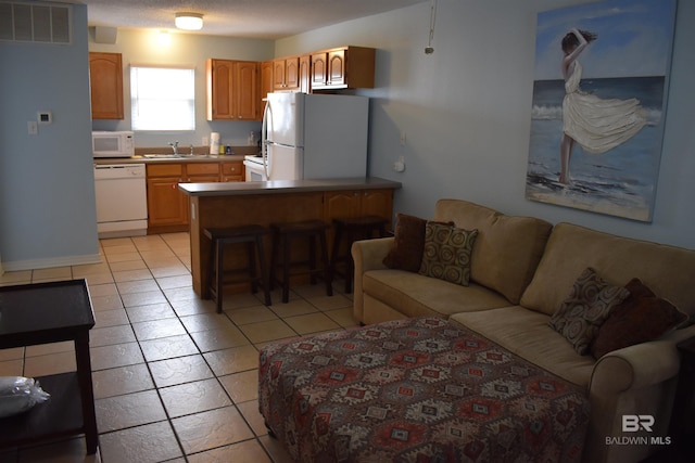 living room with light tile patterned floors, a textured ceiling, and sink