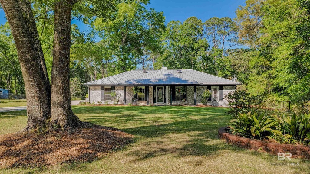 rear view of house featuring a porch, a yard, and metal roof