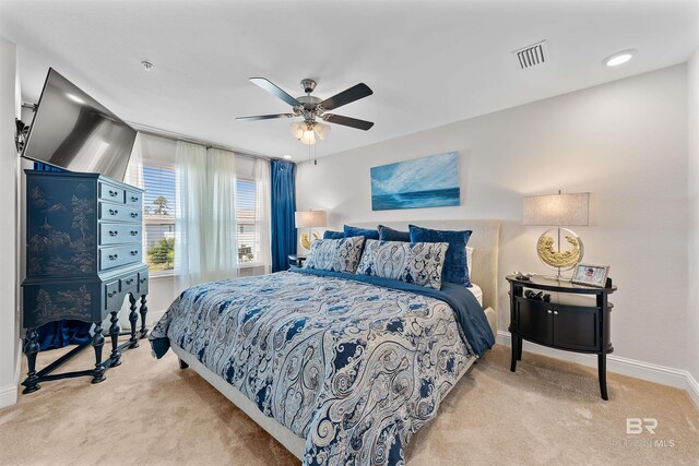 bedroom with baseboards, visible vents, a ceiling fan, and light colored carpet