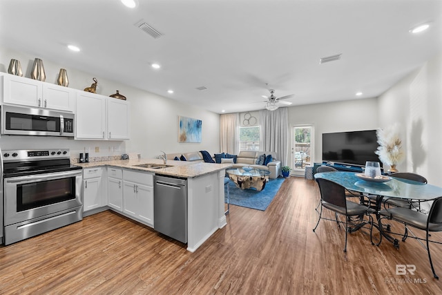 kitchen with white cabinets, visible vents, a sink, appliances with stainless steel finishes, and open floor plan