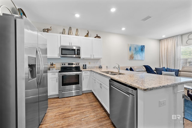kitchen with open floor plan, appliances with stainless steel finishes, a sink, and white cabinetry