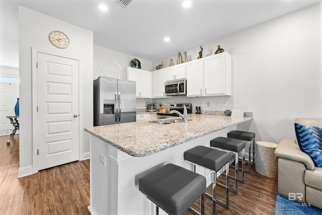 kitchen with a peninsula, dark wood finished floors, appliances with stainless steel finishes, and a sink