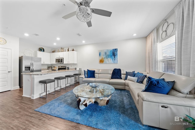living room with visible vents, baseboards, recessed lighting, wood finished floors, and ceiling fan