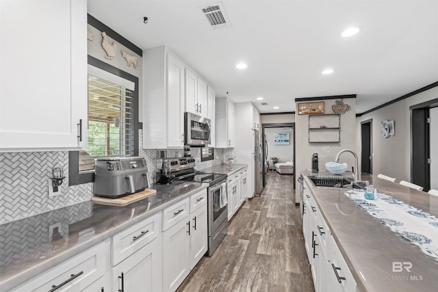 11691 Grantham Rd, Foley, AL 36535 - kitchen with appliances with stainless steel finishes, white cabinetry, dark wood-style flooring, backsplash, and recessed lighting
