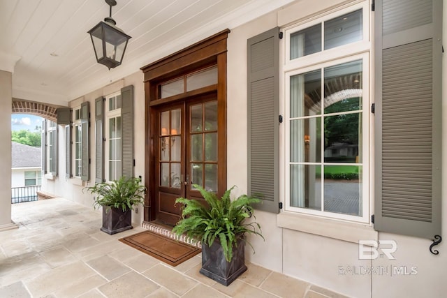 view of exterior entry featuring french doors and a porch