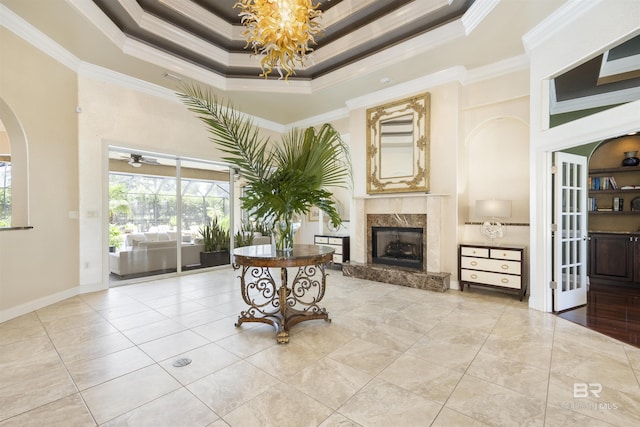 living area featuring a fireplace, a raised ceiling, a wealth of natural light, and crown molding