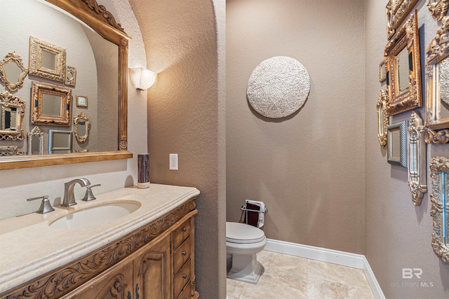 bathroom featuring vanity, toilet, and baseboards