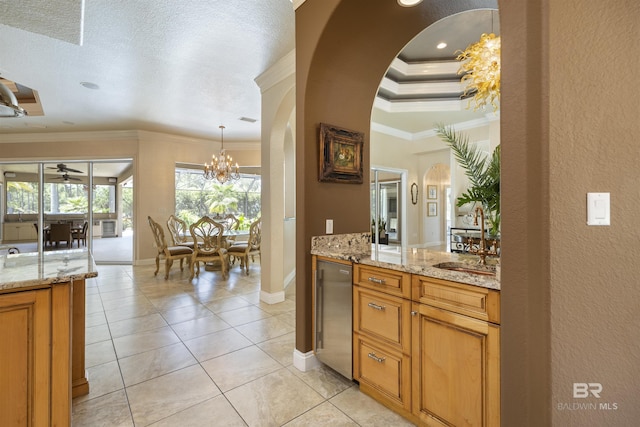 kitchen featuring hanging light fixtures, brown cabinetry, light stone countertops, and crown molding