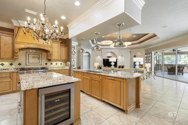 kitchen with light stone counters, a large island, a raised ceiling, open floor plan, and beverage cooler