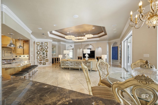 interior space with arched walkways, a chandelier, baseboards, a tray ceiling, and crown molding