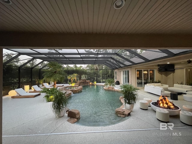 view of pool featuring a patio, glass enclosure, an outdoor living space with a fire pit, and a pool with connected hot tub