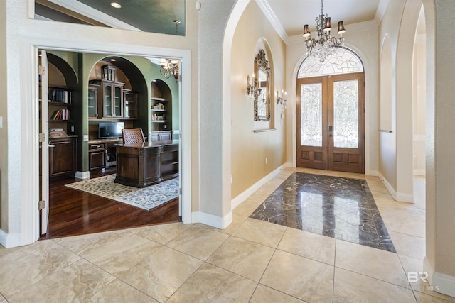 foyer entrance with baseboards, french doors, an inviting chandelier, and crown molding