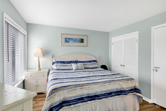 bedroom with baseboards, wood finished floors, and a closet