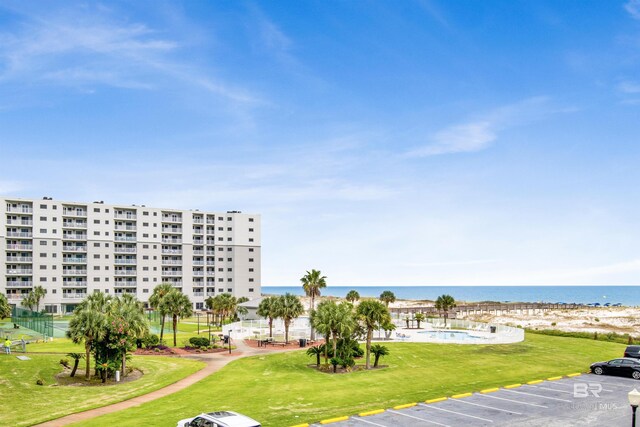 view of property's community featuring a lawn, a water view, and uncovered parking