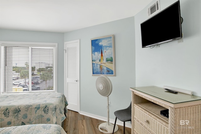 bedroom featuring baseboards, wood finished floors, and visible vents