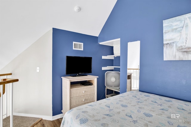 bedroom with visible vents, baseboards, wood finished floors, and high vaulted ceiling