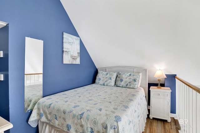 bedroom with vaulted ceiling and wood finished floors