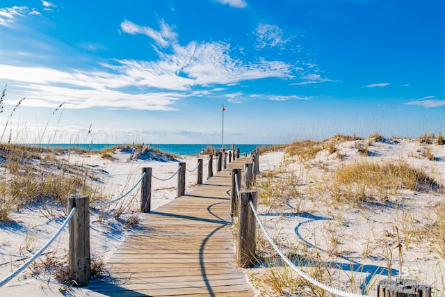 view of dock featuring a water view and a beach view